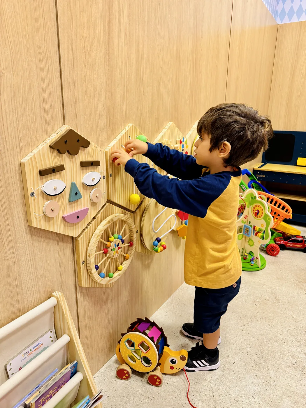 Criança brincando com painéis de madeira na brinquedoteca